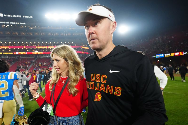 Nov 29, 2025; Los Angeles, California, USA; Southern California Trojans head coach Lincoln Riley walks with wife Caitlin Riley after the game against the UCLA Bruins at United Airlines Field at Los Angeles Memorial Coliseum. Mandatory Credit: Kirby Lee-Imagn Images