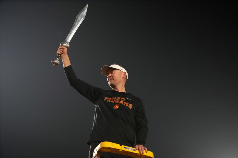 Nov 29, 2025; Los Angeles, California, USA; Southern California Trojans head coach Lincoln Riley leads the Spirit of Troy marching band in a rendition of Tribute to Troy after teh game against the UCLA Bruins at United Airlines Field at Los Angeles Memorial Coliseum. Mandatory Credit: Kirby Lee-Imagn Images