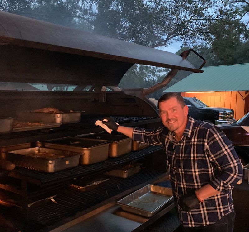 Chef and pitmaster Tommy Nevill works the smoker at a barbecue event.