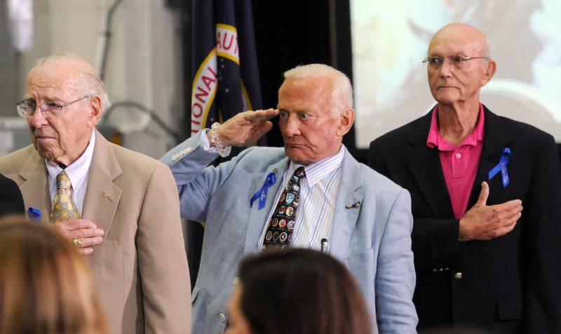 NASA astronauts Jim Lovell, left, Buzz Aldrin and Michael Collins stand for the National Anthem during a ceremony Monday, July 21, 2014, renaming the operations and checkout building at Kennedy Space Center in Florida for astronaut Neil Armstrong. The iconic building houses astronaut crew quarters and was where the Orion capsule was being developed. Lovell died Aug. 7, 2025. Collins died April 28, 2021.