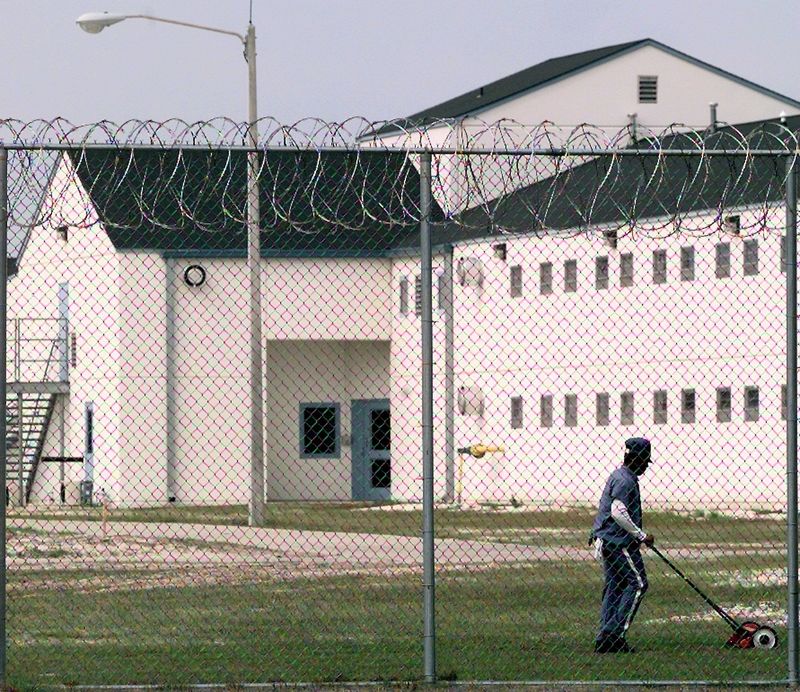 A man mows the grass behind the barbed wire at the Leon County Detention facility in this file photo.