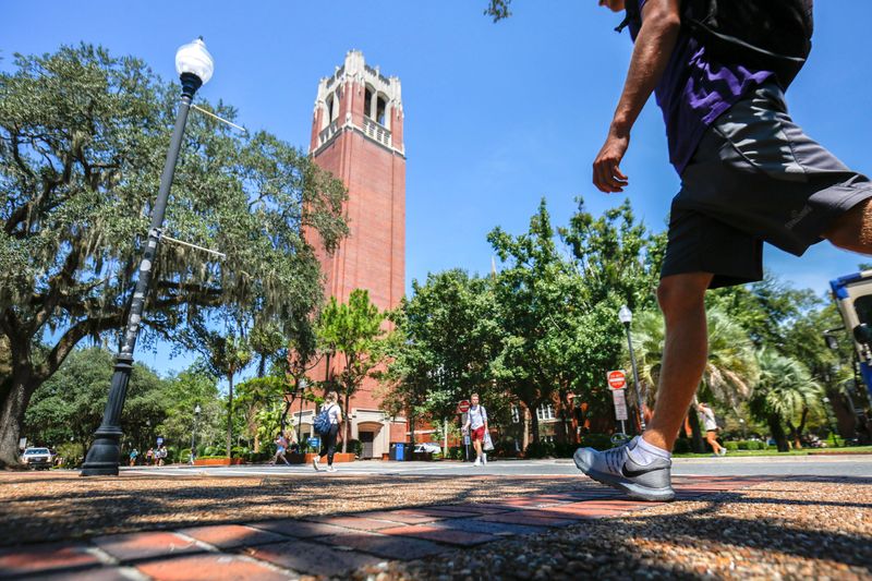 Students walk through the University of Florida campus with Century Tower in the background.