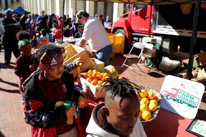 Children line up to grab fruit from the Farm Share booth during Children's Day at the Capitol on Tuesday, Jan. 28, 2020.