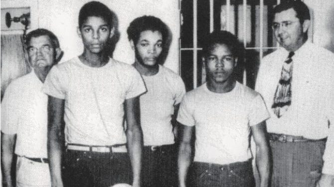 The surviving members of the Groveland Four pictured in 1949 — Charles Greenlee, Sammy Shepherd and Walter Irvin — pictured in custody alongside Lake County Sheriff Willis V. McCall