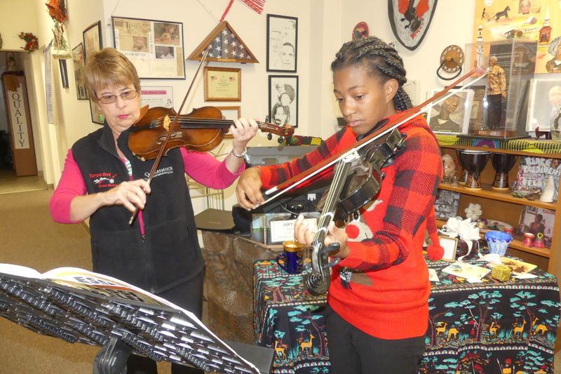 Amina Green of Royal and a junior at Wildwood Middle High School, plays Christmas carols on violin with mentor Debbie Desset of The Villages during the Christmas celebration at Royal. [Linda Florea/Correspondent]