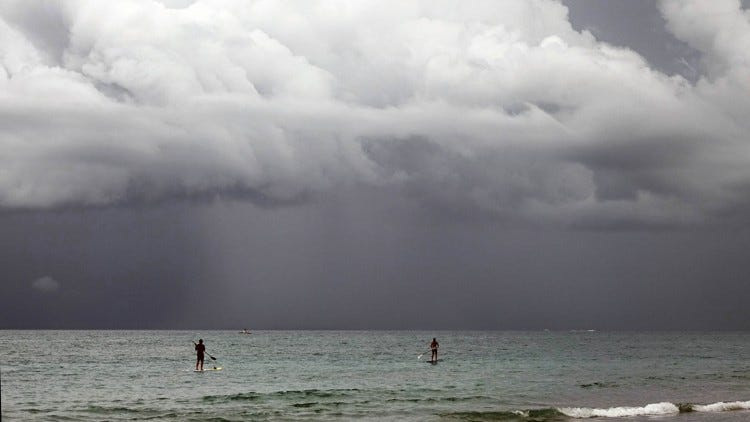 Paddle boarders off Jupiter beach as the weather rolls in Sunday morning. (Melanie Bell / The Palm Beach Post)