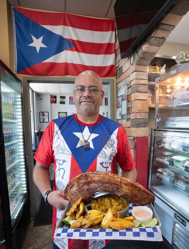 Owner Joe Perez holds a Chuleta Khan Khan entrée at Joe's Caribe Restaurant and Bakery on North 9th Avenue in Pensacola on Tuesday, Sept. 19, 2023.