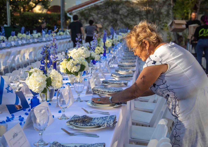 Palm Beach Synagogue member and volunteer Elsa Malinsky helps to set up a Shabbat table in the synagogue's parking lot on Nov. 10, 2023, to host dinner for 240 people, representing the number of hostages being held by Hamas.