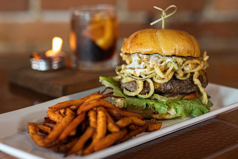 Fin & Flame Grill and Oyster Bar in Palm City features the Flame Burger, 8 ounces of premium blend of brisket, short rib and chuck, topped with aged cheddar, roasted garlic aioli and fried zucchini straws.