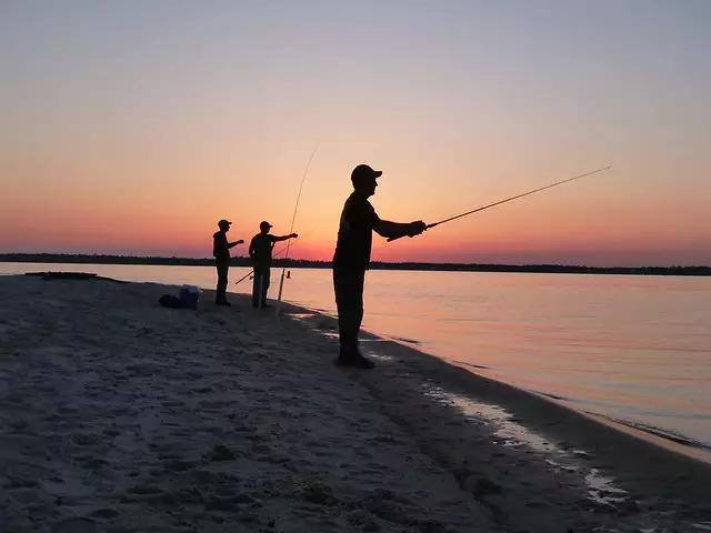 Photo of three people fishing from the beach