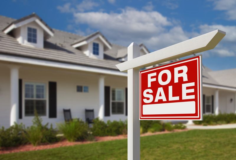 A "for sale" sign next to a house.