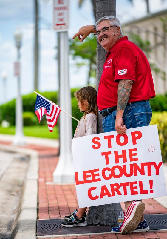 Joe Phillips and his daughter, Addy, 6, find a bit of shade during a protest outside of TM Strategic Consulting in Fort Myers on Tuesday, July 23, 2024.