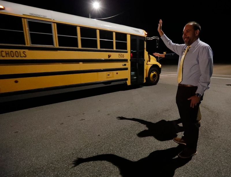 Sam Fisher, chairman of the Lee County School Board, waves to school bus drivers as they depart the west zone bus compound in Cape Coral for their routes Monday morning, August 12, 2024.