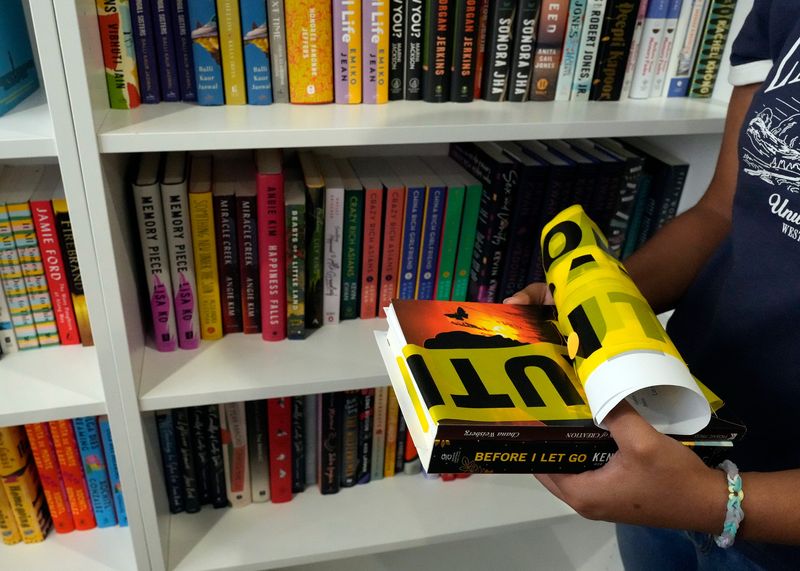 A person is pictured holding books at the Banned Book Week event at Fern & Fable Books in Ormond Beach, Saturday, Sept. 21, 2024.