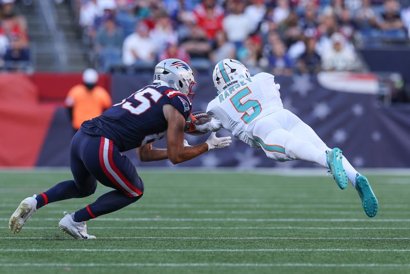 Oct 6, 2024; Foxborough, Massachusetts, USA; Miami Dolphins cornerback Jalen Ramsey (5) breaks up a pass to New England Patriots tight end Hunter Henry (85) during the second half at Gillette Stadium. Mandatory Credit: Paul Rutherford-Imagn Images