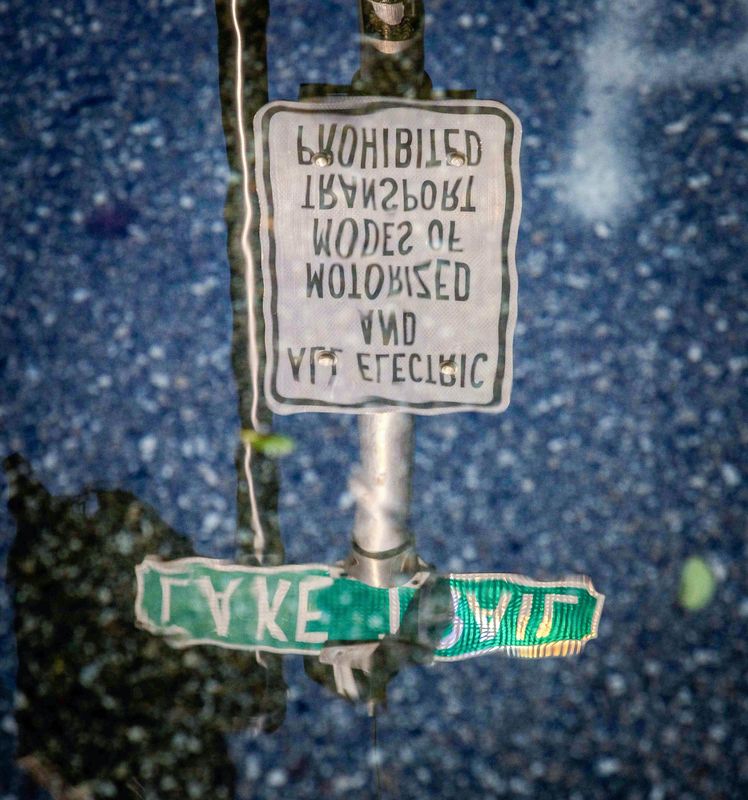 A traffic sign is reflected in water from flooding caused by a king tide on the Lake Trail near Seaspray Avenue in Palm Beach on Sept. 18, 2024.