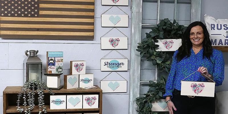 Melanie O'Neil, co-owner of the Rustic Marlin retail store in Hanover, holds one of many signs the business made in February 2023 to benefit the Blue Dot Project, which raises awarenss and funds for those dealing with maternal mental health.