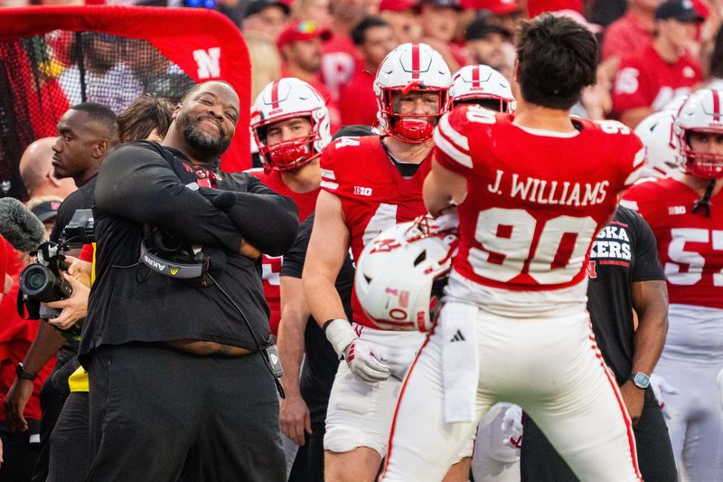 Oct 5, 2024; Lincoln, Nebraska, USA; Nebraska Cornhuskers assistant coach Terrance Knighton and defensive lineman James Williams (90) celebrate after a turnover on downs against the Rutgers Scarlet Knights during the fourth quarter at Memorial Stadium. Mandatory Credit: Dylan Widger-Imagn Images