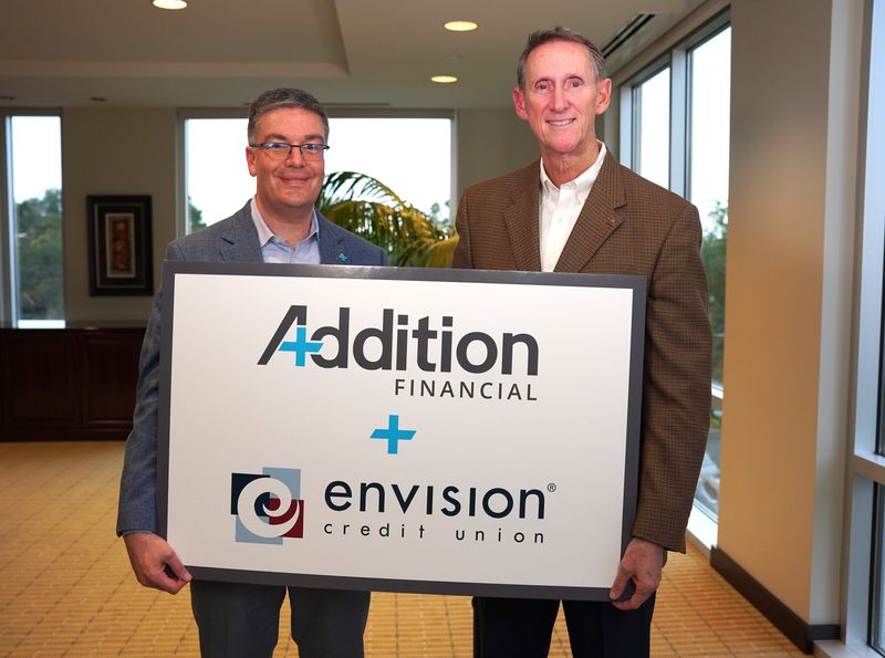 Addition Financial Credit Union President and CEO Kevin Miller holds merger sign with Darryl Worrell, president and CEO of Envision Credit Union.