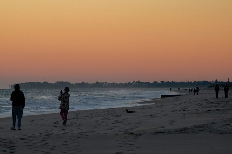 People walk Sexton Plaza Beach bundled up at sunrise, Thursday, Jan. 9, 2025, in Vero Beach. A cold front associated with a winter storm impacting Midwest and Mid-Atlantic states drove low temperatures into the low-to-mid 40s this week, a meteorologist said. With 10-15 mph winds, 40s felt like the mid-30s in some areas of the Treasure Coast.