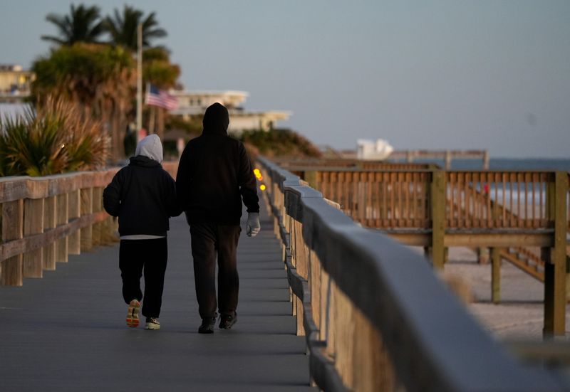 People walk Conn Beach Boardwalk bundled up at sunrise, Thursday, Jan. 9, 2025, in Vero Beach. A cold front associated with a winter storm impacting Midwest and Mid-Atlantic states drove low temperatures into the low-to-mid 40s this week, a meteorologist said. With 10-15 mph winds, 40s felt like the mid-30s in some areas of the Treasure Coast.