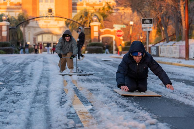Matt Ramos, right, and Aaron Litavsky sled down College Avenue in front of Westcott Fountain, Wednesday, Jan. 22, 2025.