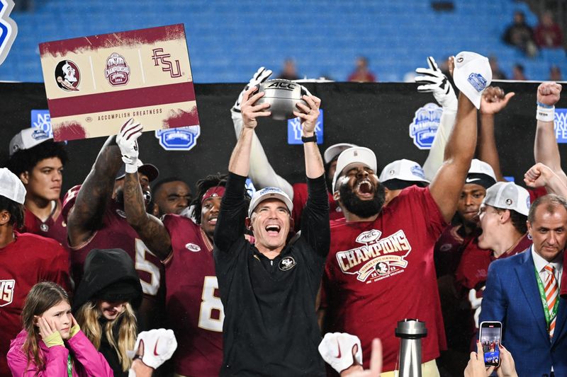 Dec 2, 2023; Charlotte, NC, USA; Florida State Seminoles head coach Mike Norvell raises the ACC Championship trophy with his players after the game against the Louisville Cardinals at Bank of America Stadium. Mandatory Credit: 
Bob Donnan-USA TODAY Sports