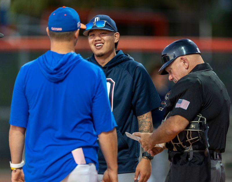 Dwyer high school baseball head coach Jordan Yamamoto, center, talks to Palm Beach Gardens High School baseball head coach Matthew Judkins before their game in Palm Beach Gardens, Florida on February 12, 2025.