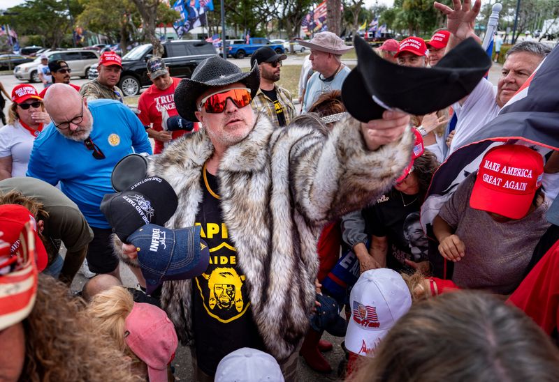 Proud Boys member Joe Biggs hands out hats to Trump supporters at a President's Day rally 
across the street fromTrump International Golf Club in West Palm Beach, Florida on February 17, 2025. Biggs had been serving 17 years in prison on seditious conspiracy charges for his role in the Jan. 6 attack until Trump commuted his sentence.