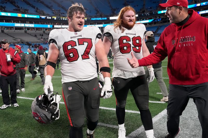 Dec 1, 2024; Charlotte, North Carolina, USA; Tampa Bay Buccaneers offensive tackle Luke Goedeke (67) and guard Cody Mauch (69) leave the field after the game at Bank of America Stadium. Mandatory Credit: Bob Donnan-Imagn Images