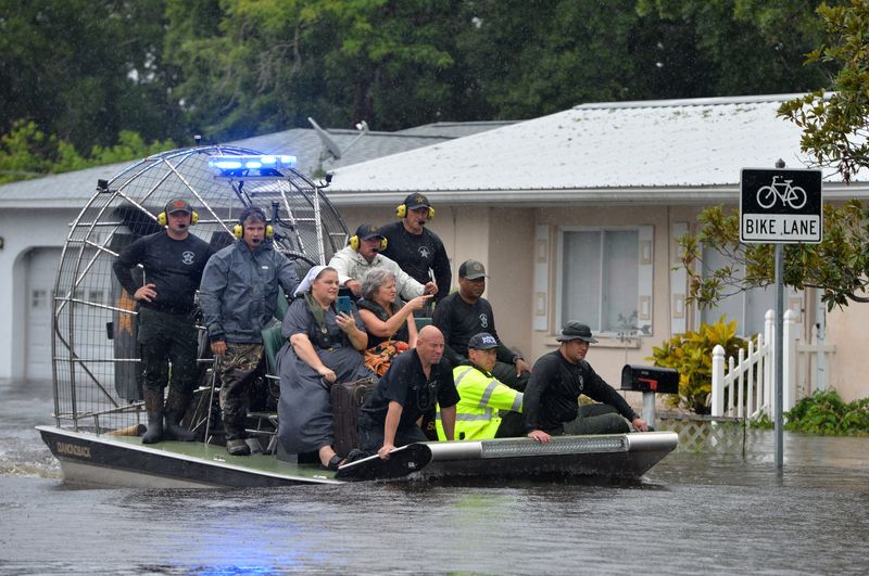 An airboat carrying evacuees from the Pinecraft neighborhood approaches dry land Monday afternoon Aug. 5, 2024 as multiple law enforcement and rescue agencies conduct evacuations in the area along Phillippi Creek following Tropical Storm Debby.
