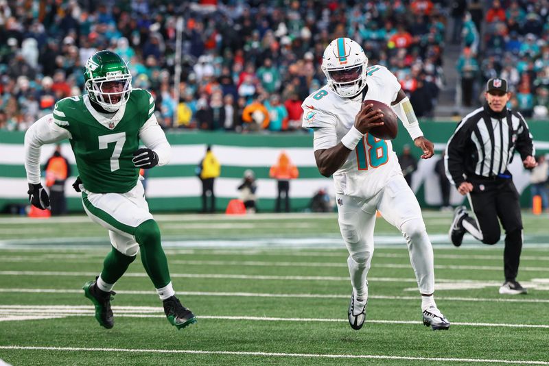 Jan 5, 2025; East Rutherford, New Jersey, USA; Miami Dolphins quarterback Tyler Huntley (18) runs with the ball while being pursued by New York Jets defensive end Haason Reddick (7) during the second quarter at MetLife Stadium. Mandatory Credit: Ed Mulholland-Imagn Images