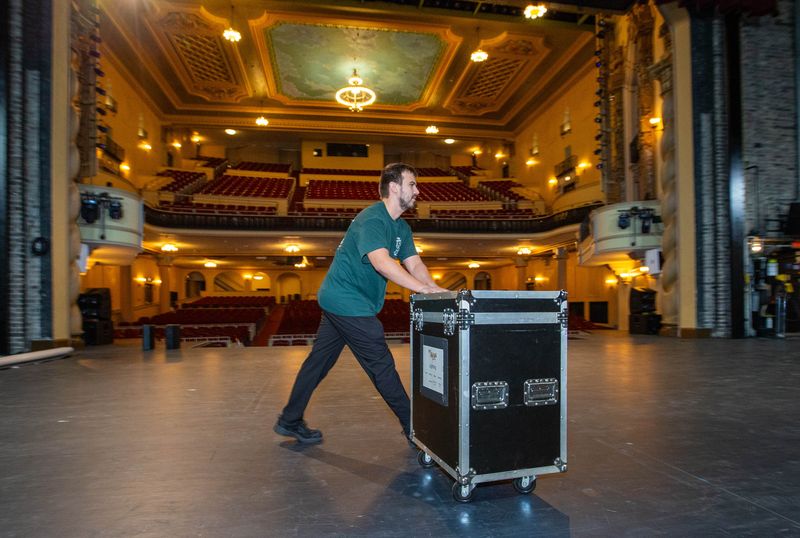Celtic Angels audio engineer Alex Simikian rolls equipment onto the stage in preparation for a performance at the Saenger Theatre in downtown Pensacola on Monday, March 17, 2025. The theater opened in 1925 and is celebrating its 100th anniversary.