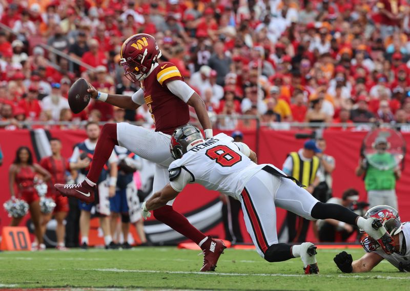 Sep 8, 2024; Tampa, Florida, USA; Washington Commanders quarterback Jayden Daniels (5) runs past Tampa Bay Buccaneers linebacker SirVocea Dennis (8) for a touchdown during the second half at Raymond James Stadium. Mandatory Credit: Kim Klement Neitzel-Imagn Images