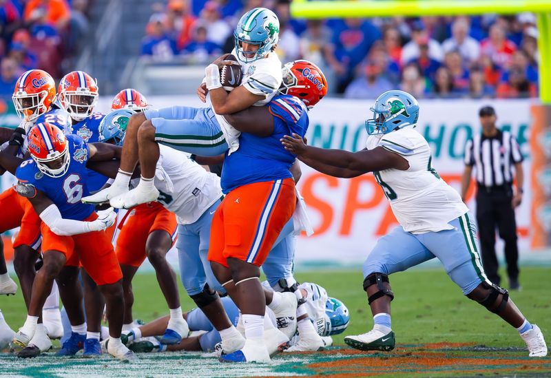 Florida Gators defensive lineman Desmond Watson (21) tackles Tulane Green Wave quarterback Ty Thompson (7) during the first half at Raymond James Stadium in Tampa, FL on Friday, December 20, 2024 in the 2024 Union Home Mortgage Gasparilla Bowl. [Doug Engle/Gainesville Sun]