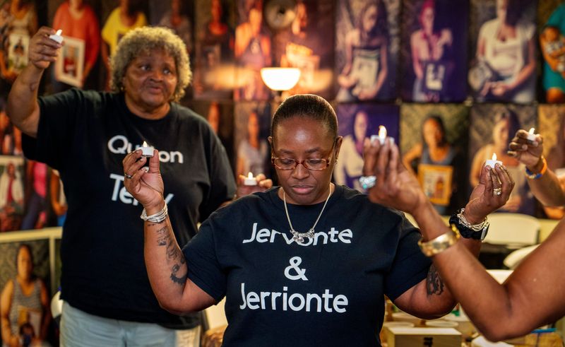Kamisha Gibson, center, and Oretha Menedez, left, hold up candles at the Mothers Against Murderers Association vigil to remember those lost to violence in West Palm Beach, Florida on April 12, 2025.