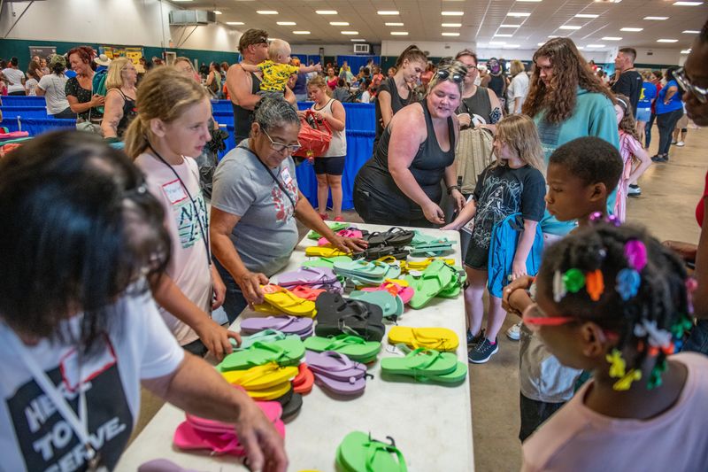 Volunteers hand out free flip-flops during the Jubilee Church Back to School Giveaway at the Pensacola Interstate Fairgrounds Saturday, August 5, 2023. The event included free backpacks, food, haircuts, school supplies and more.