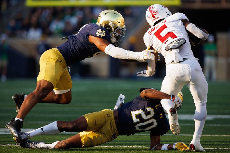 Notre Dame corner back Benjamin Morrison (20) and linebacker Jaiden Ausberry (4) tackle Stanford running back Chris Davis Jr. (5) during a NCAA college football game between Notre Dame and Stanford at Notre Dame Stadium on Saturday, Oct. 12, 2024, in South Bend.