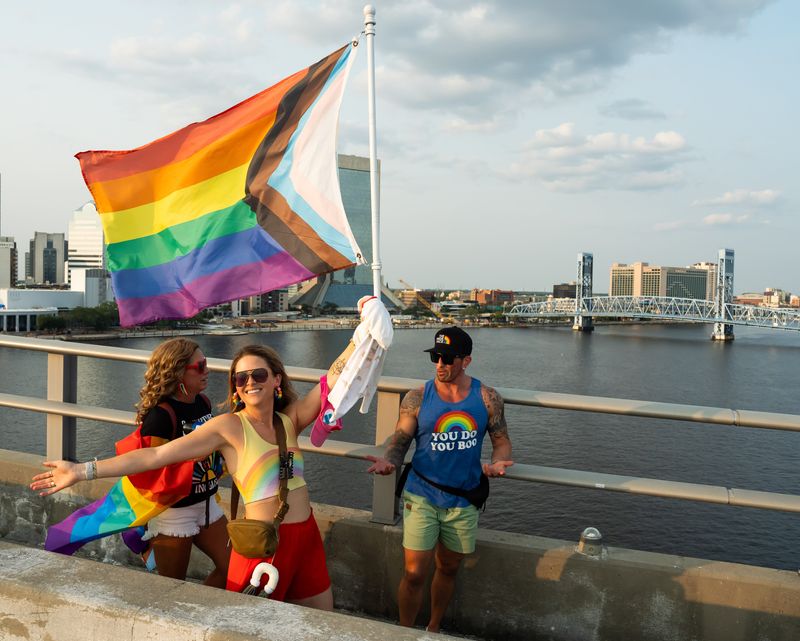 Mandy Rubin struts across the Acosta Bridge with a gay pride flag as Jacksonville's LGBTQ+ community and its supporters held two related events to kick off Pride Month Sunday June 1, 2025 in downtown Jacksonville, Fla. The first was the annual march across the Acosta Bridge. Participants carried Pride flags and signs. The second was the community bridge lighting of the Acosta Bridge after the Main Street Bridge was scheduled for maintenance. The Acosta Bridge was bathed in yellow, purple, blue, green orange and red lights. [Doug Engle/Florida Times-Union]