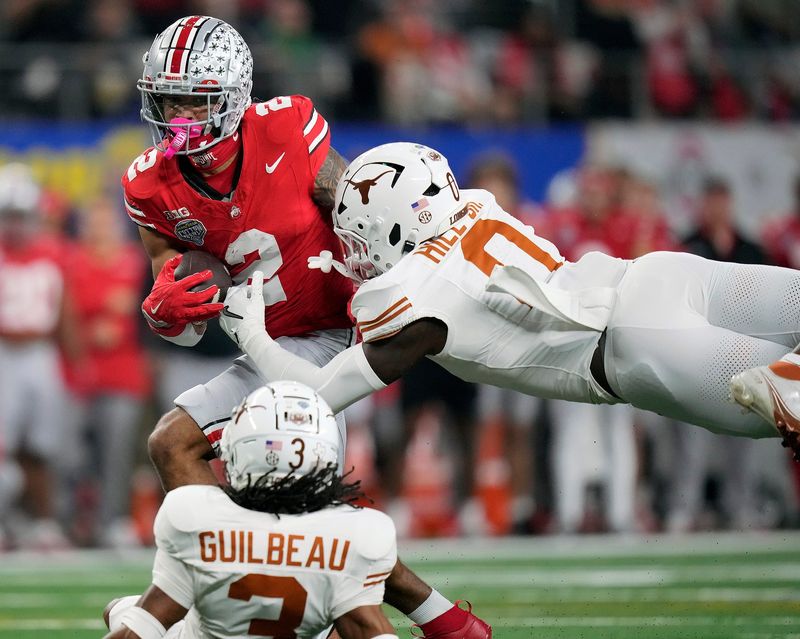 Ohio State Buckeyes wide receiver Emeka Egbuka (2) makes a catch against Texas Longhorns defensive back Jaylon Guilbeau (3) and linebacker Anthony Hill Jr. (0) in the first quarter of the Cotton Bowl Classic during the College Football Playoff semifinal game at AT&T Stadium in Arlington, Texas on January, 10, 2025.