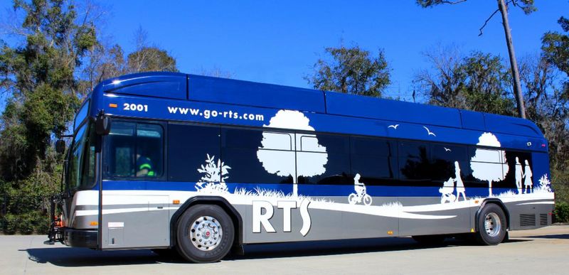 An RTS bus displayed parked next to a few trees.