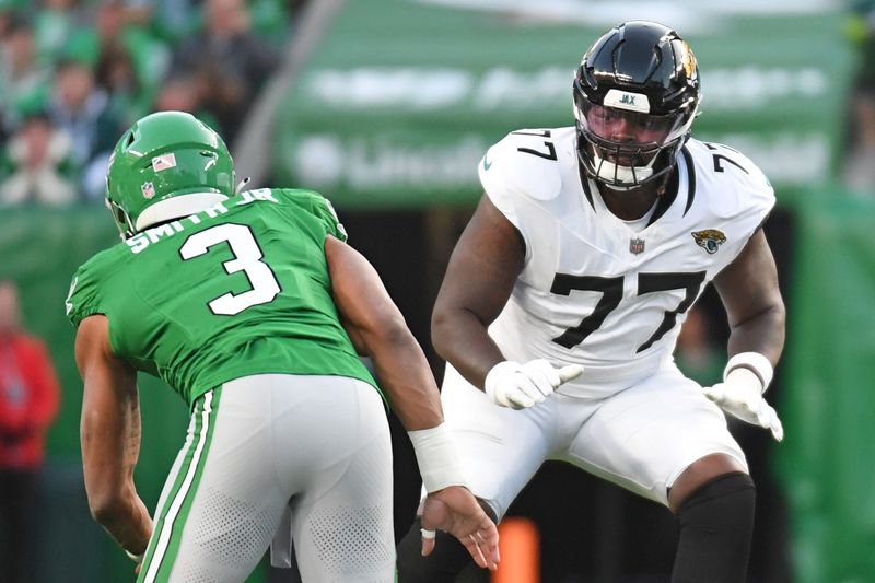 Nov 3, 2024; Philadelphia, Pennsylvania, USA; Jacksonville Jaguars offensive tackle Anton Harrison (77) prepares to block Philadelphia Eagles linebacker Nolan Smith Jr. (3) at Lincoln Financial Field. Mandatory Credit: Eric Hartline-Imagn Images