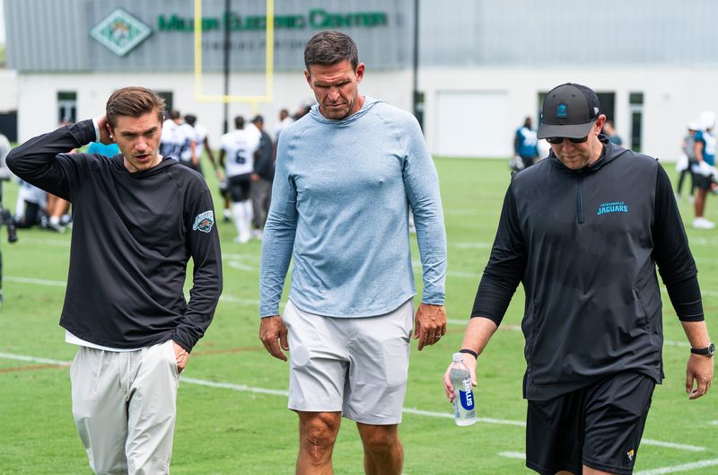 Jacksonville Jaguars general manager James Gladstone, left, Jacksonville Jaguars is executive vice president of football operations Tony Boselli, center and Jacksonville Jaguars head coach Liam Coen, right, all talk on the field after the Jacksonville Jaguars’ mandatory minicamp Tuesday June 10, 2025 at the Miller Electric Center in Jacksonville, Fla. [Doug Engle/Florida Times-Union]
