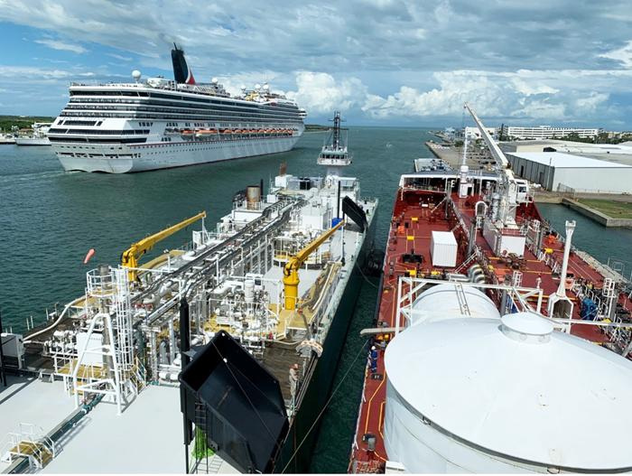 The liquefied natural gas bunker barge Clean Canaveral, at left in foreground, is alongside the tanker Damia Desgagnes for the first barge-to-cargo-ship bunkering of LNG at Port Canaveral’s South Cargo Berth 4 in 2023. A Carnival Cruise Line cruise ship passes in the background.