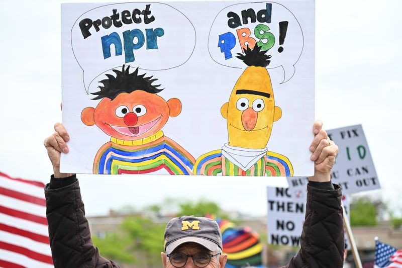 A protester holds up a handmade sign featuring Bert and Ernie from "Sesame Street" with the message “Protect NPR and PBS” during the No Kings Day demonstration in Petoskey on Saturday, June 14, 2025.