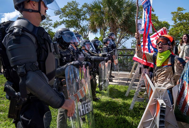 Protesters stand behind a barricade as Palm Beach County Sheriff's Deputies block the road near President Trump's Mar-a-Lago home during a "No Kings Day" protest on June 14, 2025 in Palm Beach, Florida.