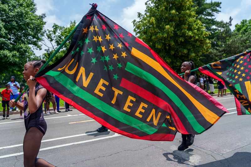 Members of the Royal Family dance crew carry Juneteenth flags at the front of their entry in the Ernestine Jackson Juneteenth Freedom Day Parade on Saturday, June 15, 2025 on MacArthur Highway in Peoria.