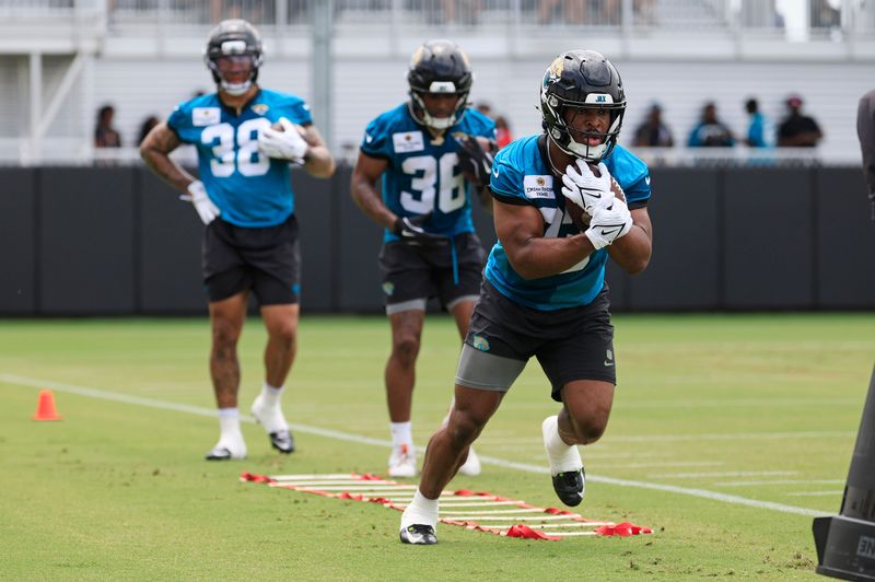 Jacksonville Jaguars running back Bhayshul Tuten (33) runs the ball followed by running back LeQuint Allen (36) and running back Jaâ€™Quinden Jackson (38) during a rookie minicamp at Miller Electric Center Saturday, May 10, 2025 in Jacksonville, Fla. [Corey Perrine/Florida Times-Union]