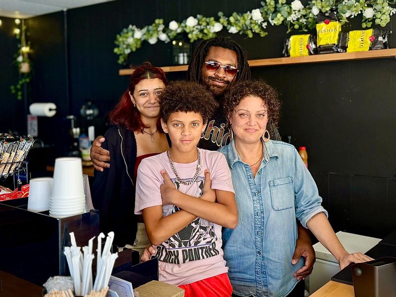 Brianna Martinez (left) and Quincy Gibbs pose for a photo with parents and Coffee by KADA owners Keone Gibbs and Adalicia Abu-Rus inside their first brick-and-mortar cafe in South Daytona.