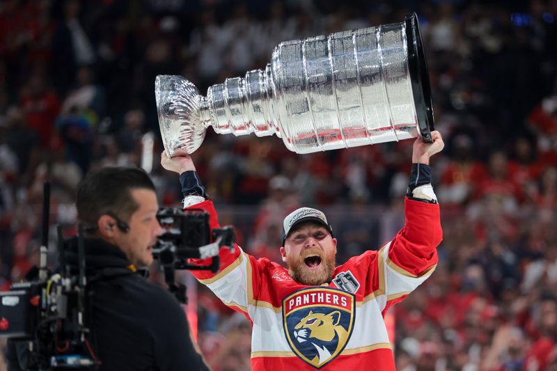 Jun 17, 2025; Sunrise, Florida, USA; Florida Panthers center Sam Bennett (9) hoists the Stanley Cup after winning game six of the 2025 Stanley Cup Final against the Edmonton Oilers at Amerant Bank Arena. Mandatory Credit: Sam Navarro-Imagn Images
